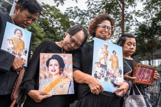 People hold portraits of Thailand's former Queen Sirikit as they gather in front of C