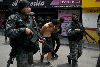 Police officers escort suspects arrested in Rio's favelas
