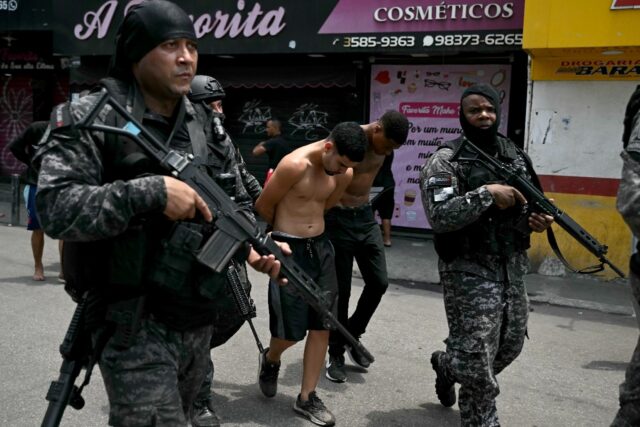 Police officers escort suspects arrested in Rio's favelas