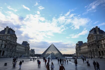 Tourists stroll near the Louvre Pyramid, designed by Chinese-US architect Ieoh Ming Pei, a