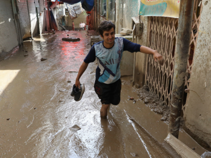 A man wades in mud after flash flooding at Imamzadeh Davood village in the northwestern pa