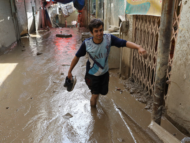 A man wades in mud after flash flooding at Imamzadeh Davood village in the northwestern pa