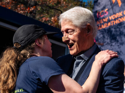 Former President Bill Clinton hugs his daughter, Chelsea Clinton, after Chelsea crossed th