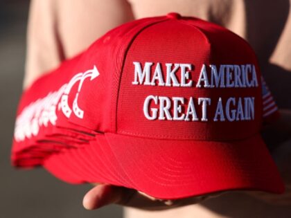 A member of Turning Point USA distributes MAGA hats to people gathered at a makeshift memo