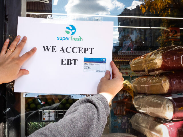 A worker places an Electronic Benefit Transfer (EBT) sign outside a grocery store in the B