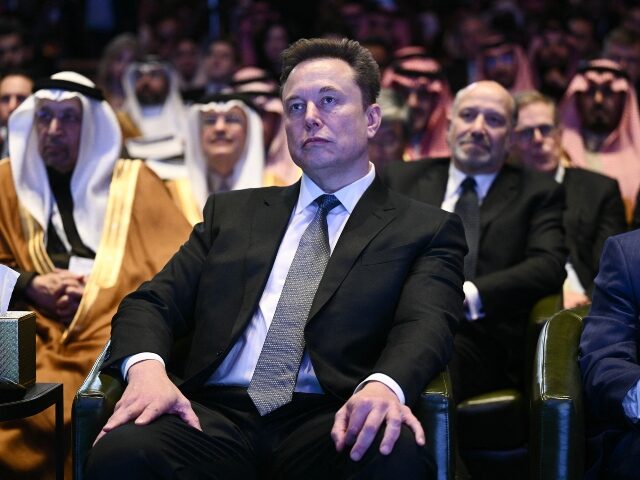 Elon Musk looks unhappy in an audience of arabs