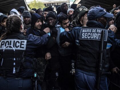 TOPSHOT - Security agents and police officers hold back migrants during the evacuation of