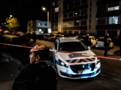 A boy wearing an Halloween mask looks away in foreground as French soldiers and Municipal