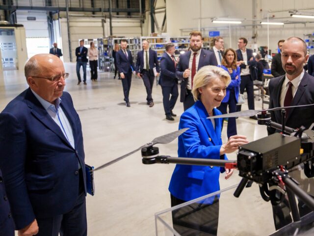 European Commission President Ursula von der Leyen (C) looks at a drone as she stands next