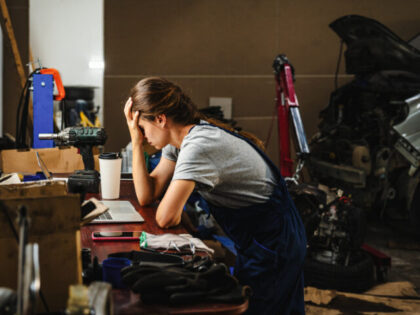 A worried woman entrepreneur in a car service shop, facing business difficulties. Bankrupt