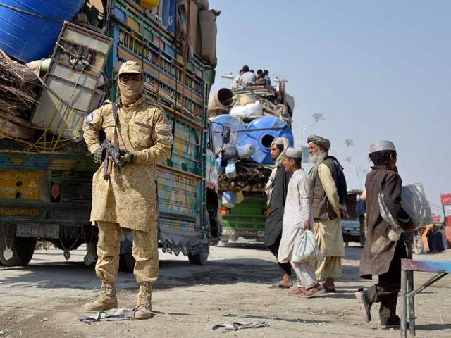 TOPSHOT - A Taliban security personnel stands guard as deported Afghan refugees from Pakis