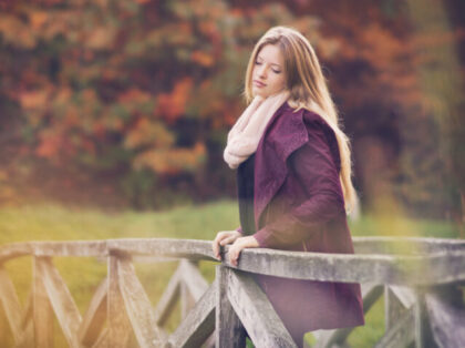 Lonely young women standing on a bridge in autumn park, with custom white balance and colo
