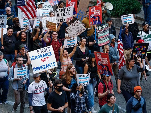 GettyImages2234004633 People hold signs as they march during a demonstration against US Immigration and Customs