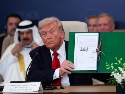 U.S. President Donald Trump poses with the signed agreement at a world leaders' summit on