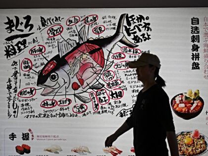 A woman walks past a Japanese restaurant in Beijing on November 19, 2025. China will suspe