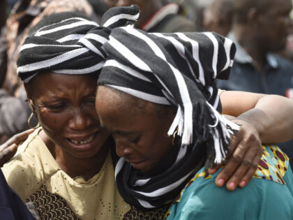 A woman cries while trying to console a woman who lost her husband during the funeral serv