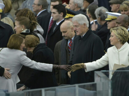 Congresswoman Nancy Pelosi (L) and former presidential candidate Hillary Clinton reach ove