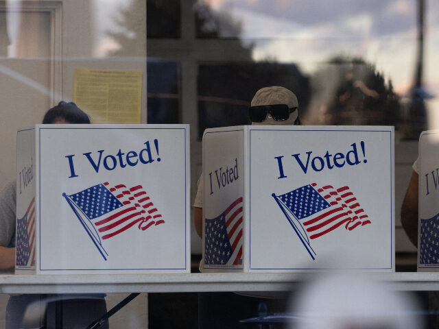 People complete their ballots as the sunset is reflected in the glass of a precinct in the