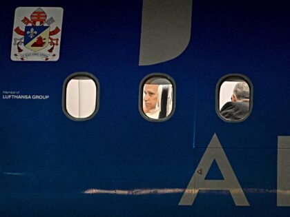 Pope Leo XIV is seen through a window sitting in his plane before taking off for Istanbul