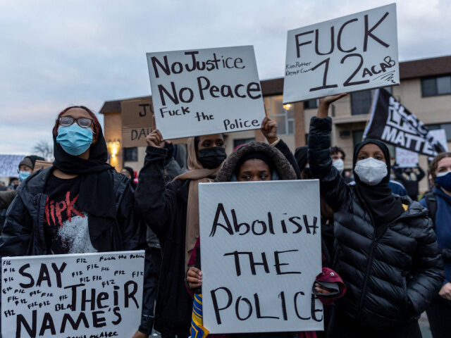 Somali American demonstrators hold signs as peaceful protests continue in front of the Bro