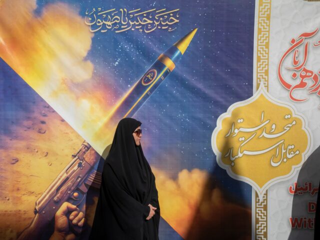 death to america TEHRAN, IRAN NOVEMBER 4: A woman stands in front of a poster featuring Iranian missiles du