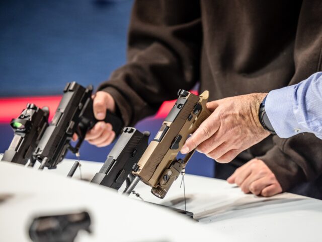 Visitors inspect firearms at the at the Sig Sauer Inc. stand during the FEINDEF defense ex