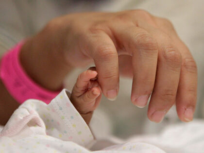 14-week-old Melinda Star Guido holds her mother's little finger while lying in an inc