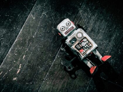 sad beat up old retro robot on a wooden floor shot from above