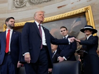 TOPSHOT - President Donald Trump, center, holds the hand of his wife Melania Trump, right,