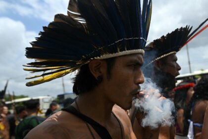 A Munduruku Indigenous man of the Ipereg Ayu movement smokes during a protest outside the