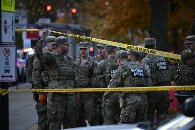 National Guard soldiers stand behind crime scene tape at a corner in downtown Washington w