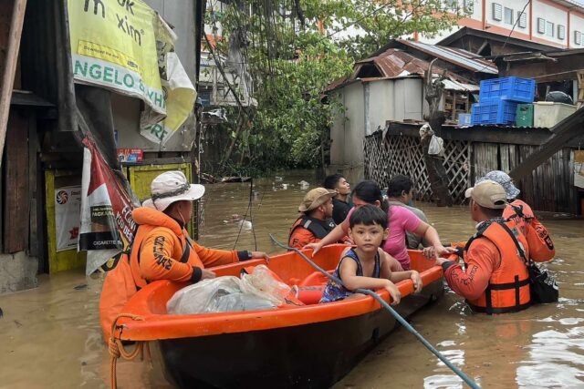 Philippine Coast Guard personnel evacuate people from their flooded homes following heavy