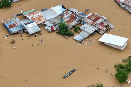 A resident paddles his boat past inundated houses in the Philippines' Tuguegarao City