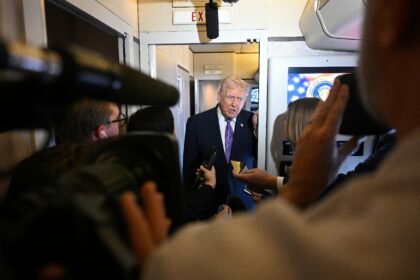 US President Donald Trump speaks to journalists aboard Air Force One while traveling home