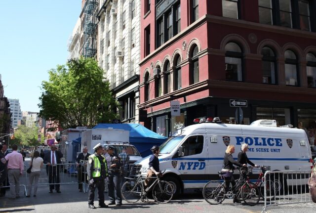 New York City police officers stand watch as investigators search for evidence in the cold