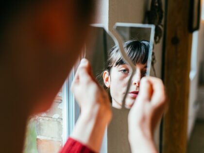 A woman peers at her broken reflection