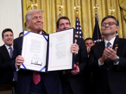 U.S. President Donald Trump holds up the “GENIUS Act” alongside Speaker of the House M