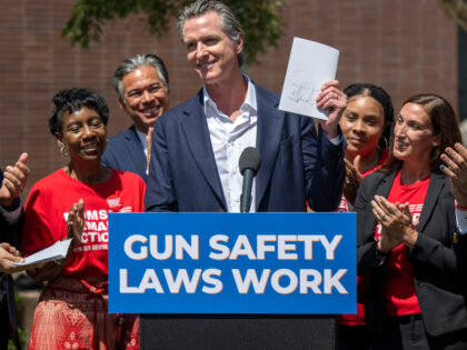 Governor Gavin Newsom holds signed gun legislation during a news conference Friday, July 2