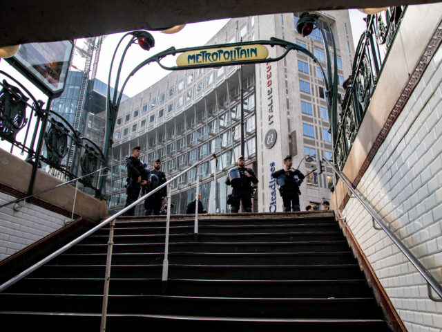 Police officers stand at the entrance steps to the metro railway station as yellow vest an