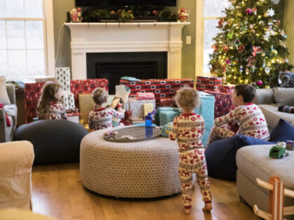 Siblings in Holiday Pajamas Check out Presents on Christmas Morning