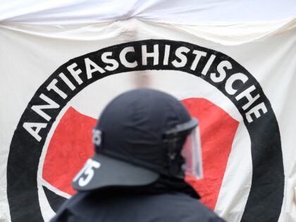 07 August 2021, Thuringia, Weimar: A policeman stands in front of an Antifa banner during