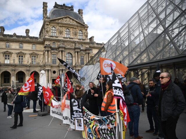 Employees hold banners and unions' flags as they block the entrance of the Musee du Louvre