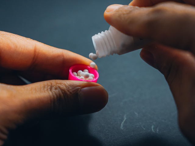 A young adult person placing colorful pills onto his fingers while seated at a table