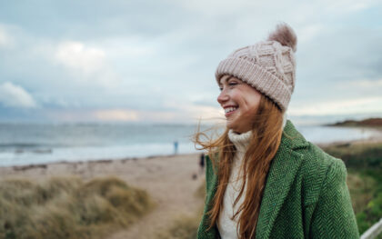 A side-view shot of a young female adult smiling whilst on a beach walk at Newton-by-the-S