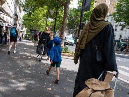 Daily life on the streets of Paris: A family rides a bicycle and a Muslim woman wearing a