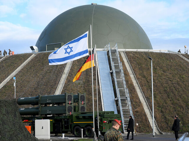 The flags of Israel and Germany fly in front of the Arrow 3 shield system and a radar dome