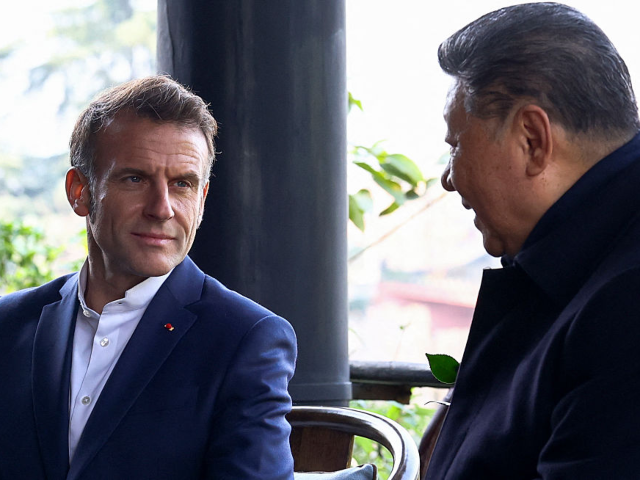 Chinese President Xi Jinping (R) speaks with French President Emmanuel Macron during a vis