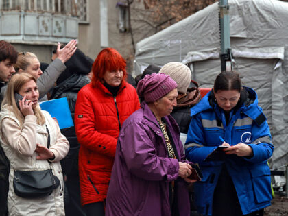 Residents of an apartment building damaged by a Russian attack are seen with a representat