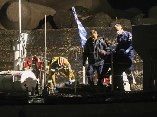 Firefighters and members of the Hellenic coast guards carry bags with bodies from a coast