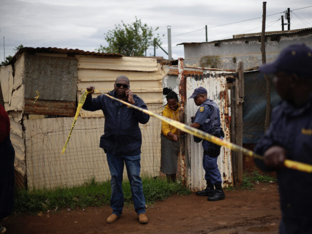 South African Police Service (SAPS) officers put up crime scene tape at the scene of an at